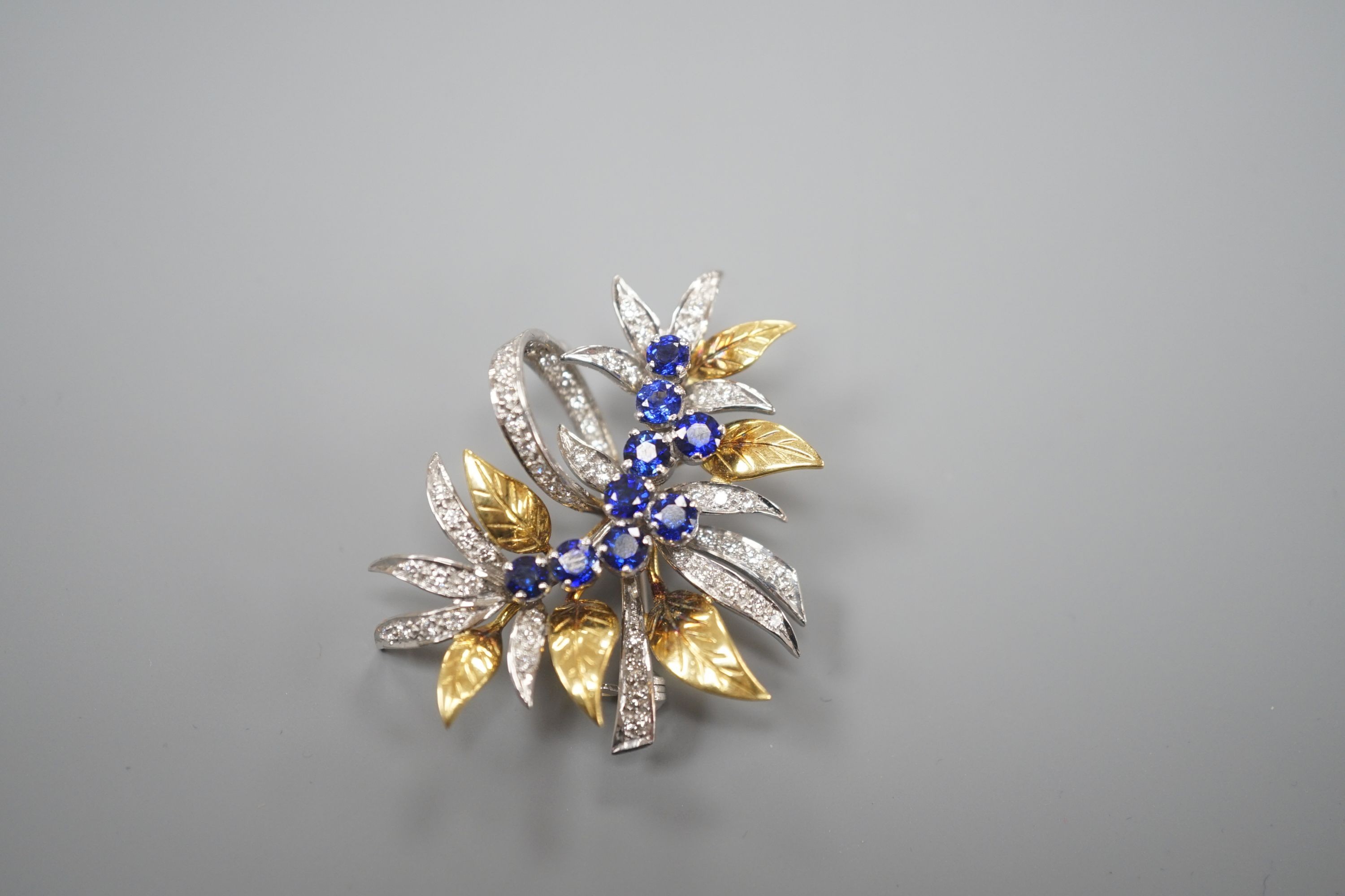 A modern 18ct two colour gold, sapphire and diamond set floral spray brooch, by Cropp & Farr, 38mm, gross weight 11.9 grams.